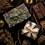 Moody floral wrapping paper by Wrapped Studios on luxury gifts with green velvet and cream satin bows.