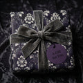 Luxury gothic wrapping paper in dark purple damask with a grey velvet bow by Wrapped Studios.