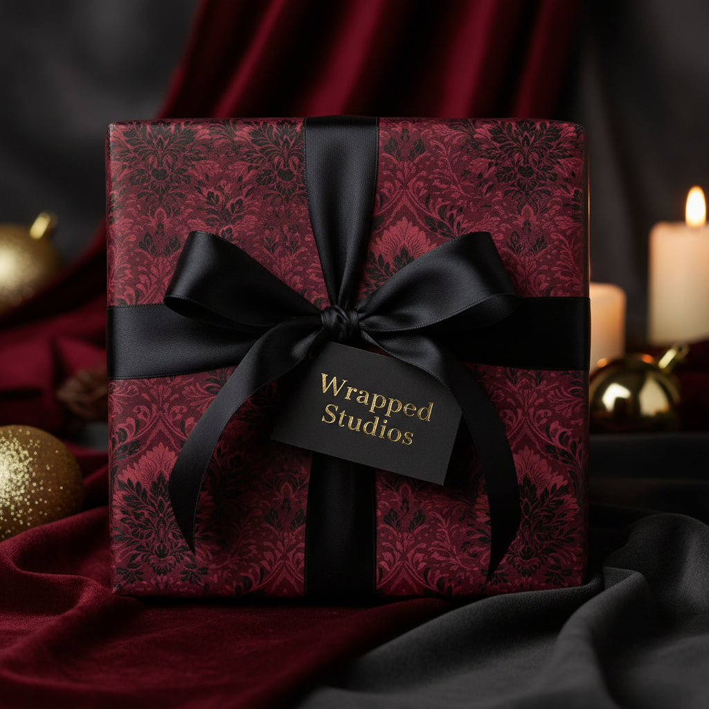 Elegant gift wrapped in burgundy floral wrapping paper, tied with a black satin ribbon and bow.