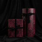 Elegant maroon and black damask wrapping paper with velvet ribbon on square and round gift boxes.
