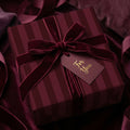 Luxury burgundy striped wrapping paper with a velvet ribbon and gift tag by Wrapped Studios.
