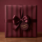 Luxury burgundy striped wrapping paper with a satin ribbon bow on a gift box by Wrapped Studios.