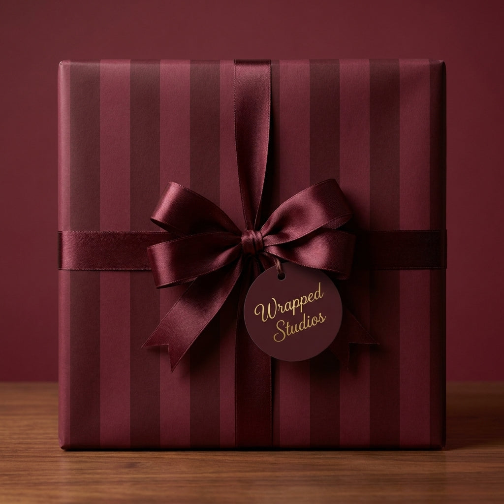 Luxury burgundy striped wrapping paper with a satin ribbon bow on a gift box by Wrapped Studios.