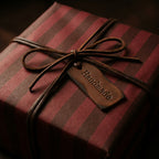 Luxury burgundy and brown striped wrapping paper with a leather bow and tag from Wrapped Studios.