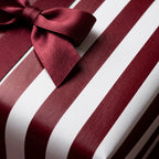 Burgundy striped wrapping paper with a luxury satin bow, elegant holiday gift wrap by Wrapped Studios.