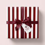Red and white striped Christmas gift wrap with a burgundy satin ribbon by Wrapped Studios.