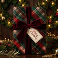Tartan Christmas wrapping paper with a red velvet bow and holiday tag by Wrapped Studios.