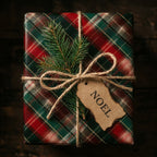 Red and green plaid Christmas wrapping paper by Wrapped Studios with twine, a pine sprig, and a Noel tag.