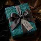 Luxury textured teal wrapping paper with a grey satin bow and Wrapped Studios gift tag.