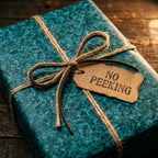 Rustic teal holiday gift wrap with twine and a "No Peeking" tag on wood, by Wrapped Studios.