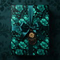 Elegant gift wrapped in dark floral wrapping paper with emerald ribbon and gift tag.