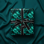 Elegant floral wrapping paper in teal and black, with a black satin bow on a silky teal background.