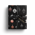 Elegant Christmas gift box with black ornament wrapping paper, black satin ribbon, and a "Merry Christmas" tag.