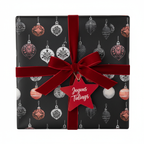 Elegant black Christmas wrapping paper with watercolor ornaments, tied with a red velvet bow and "Joyous Tidings" gift tag.