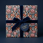 Woodland Christmas wrapping paper with deer and floral design, navy velvet ribbon by Wrapped Studios.