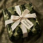 Military camouflage gift wrap with soldier silhouettes, tied with cream linen ribbon by Wrapped Studios.