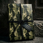 Military wrapping paper with soldier silhouettes, black paracord bow, and dog tag by Wrapped Studios.
