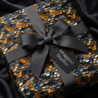 Luxury gift wrap: Scales pattern in gold, blue & black, tied with a gray ribbon and bow, set on black silky fabric.