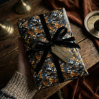 Hand holding a gift wrapped in luxury scale-patterned paper with a black velvet ribbon.