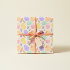 Pastel Easter wrapping paper with egg and leaf pattern, tied with a peach ribbon.
