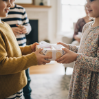 Children exchanging a gift wrapped in pastel floral wrapping paper with a white ribbon bow.