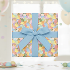 Square gift wrapped in pastel abstract patterned paper with blue ribbon.