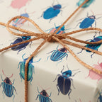 Unique beetle-print wrapping paper with metallic copper ribbon bow, ideal birthday or any occasion gift wrap.