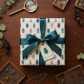 Wrapped gift in beetle-patterned wrapping paper with teal ribbon on a dark wood table.