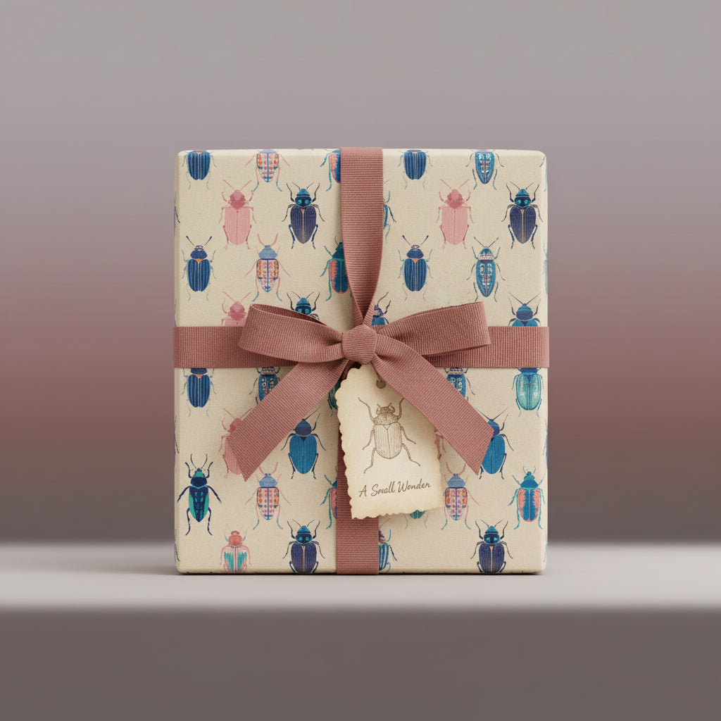 Square gift wrapped in cute beetle-print paper, tied with a mauve ribbon and a gift tag.