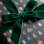 Dark academia gift wrap with beetle print and emerald velvet ribbon.