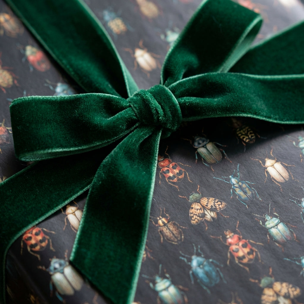 Dark academia gift wrap with beetle print and emerald velvet ribbon.