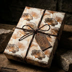 Luxury botanical wrapping paper with a gold ginkgo leaf pattern on a rustic gift by Wrapped Studios.