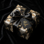 Luxury black and gold Santa Christmas wrapping paper with a satin bow, by Wrapped Studios.
