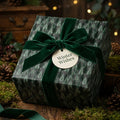 Luxury pine tree Christmas wrapping paper with a green velvet ribbon bow by Wrapped Studios.