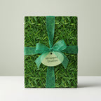 Gift wrapped in unique grass-textured wrapping paper with green ribbon.