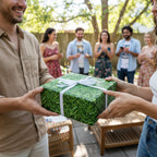 Green "grass" pattern birthday wrapping paper tied with white ribbon, being exchanged at an outdoor party.