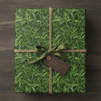 Square gift wrapped in green grass print paper with olive bow and "Thanks for always mowing" tag.