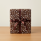 Brown polka dot wrapping paper with a matching satin ribbon bow, perfect for elegant birthday or special occasion gift wrap.
