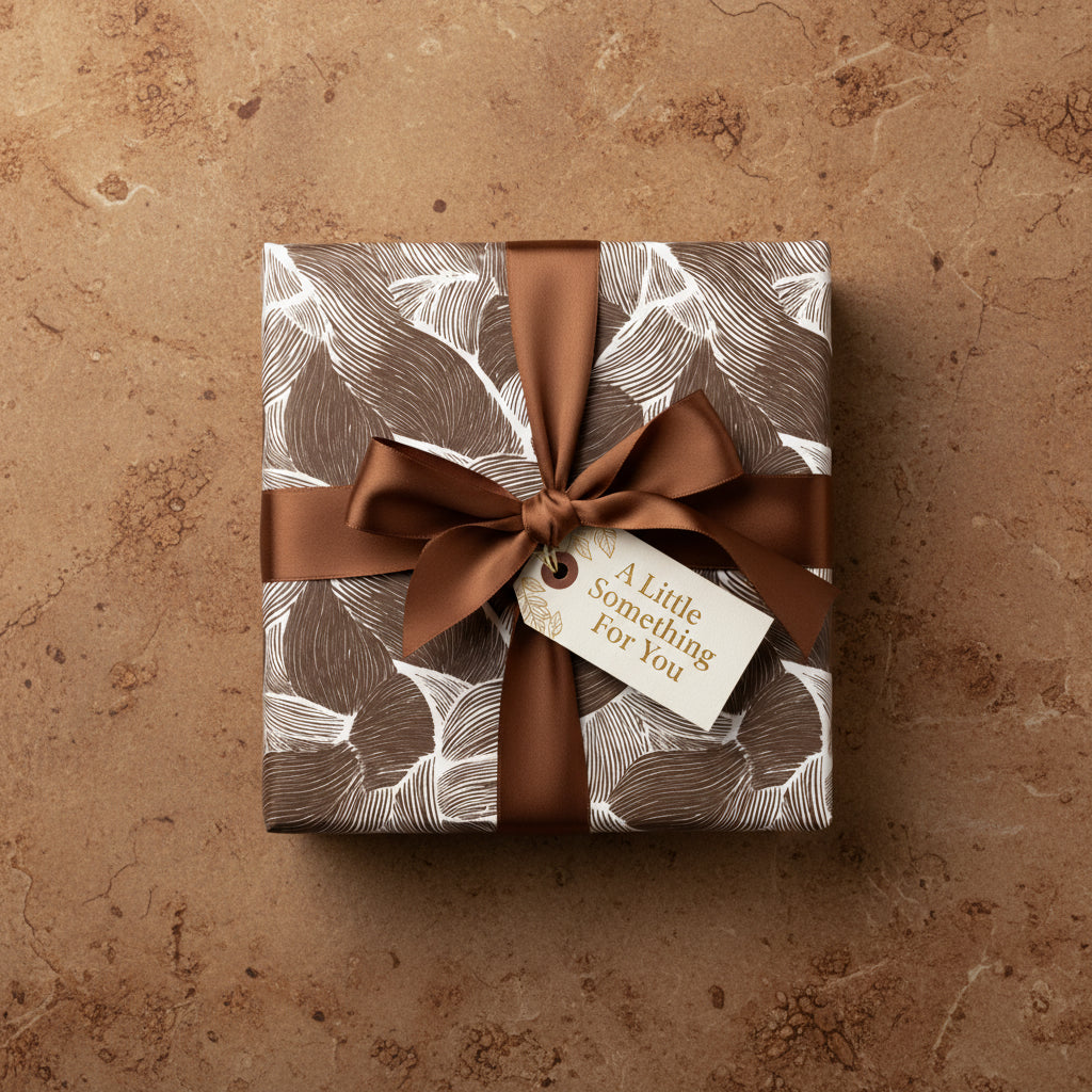 Square gift wrapped in brown leaf pattern paper with brown satin ribbon and "A Little Something For You" tag.