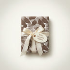 Elegant gift wrapped in brown abstract-patterned paper with a cream ribbon and "Warmest Wishes" tag.