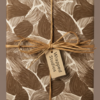 Neutral brown leaf print wrapping paper with raffia bow; minimalist botanical gift wrap.