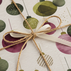 Christmas gift wrapped in modern green and purple ornament paper with natural twine and an ivory ribbon bow.