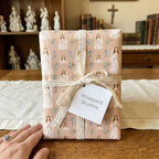 First Holy Communion wrapping paper with a praying girl pattern and lace bow by Wrapped Studios.