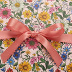 Floral wrapping paper on a gift box with a satin ribbon bow, perfect for birthday or spring celebrations.