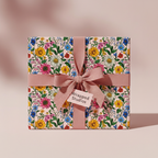 Gift box in colorful floral wrapping paper with a dusty rose ribbon and bow.