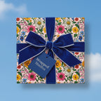 Square gift wrapped in floral wrapping paper with a blue velvet ribbon and bow.