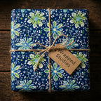 Navy floral wrapping paper from Wrapped Studios with twine bow on rustic wood.