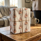 Boho guitar wrapping paper with floral details by Wrapped Studios, tied with twine on a rustic coffee table.