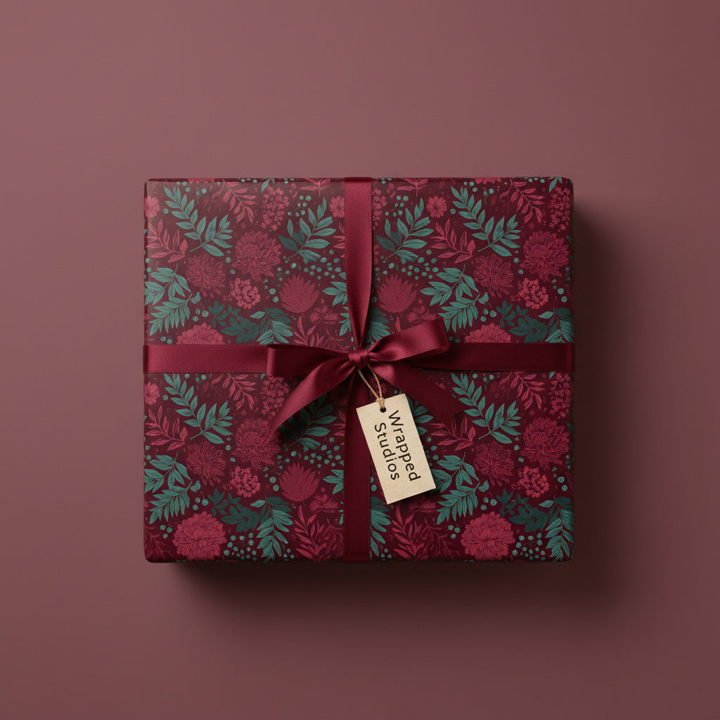 Burgundy floral wrapping paper on a square gift box, tied with a matching satin ribbon and tag.