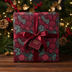 Burgundy floral Christmas gift wrap with satin ribbon and pine tree background.